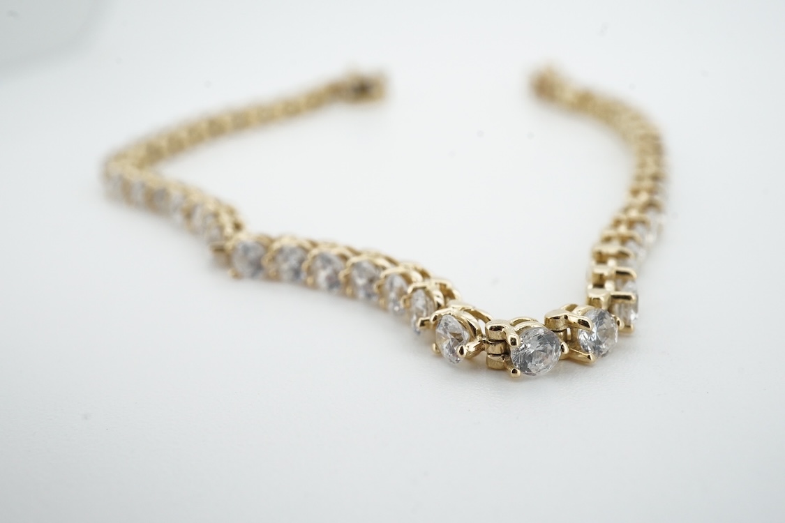 A modern yellow metal (stamped 585) and cubic zirconia set line bracelet, 18cm and a pair of similar drop earrings, together with a similar 9k and cubic zirconia set cluster ring, size N.